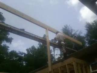 Carpenter setting a ridge beam over a new addition frame — Ice Dam Removal by Roofing Brothers in Comstock