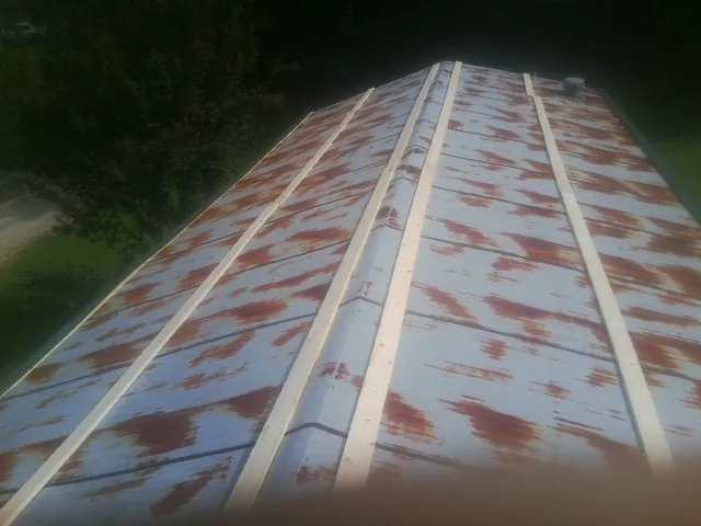 Rusted metal roof panels with new wood purlins before replacement — Storm Damage Roof Repair in Comstock by Roofing Brothers