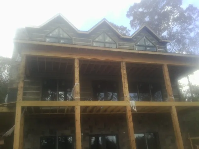 Dormers and porch framing on a large log home under construction — Roof Coating work by our crew in Comstock