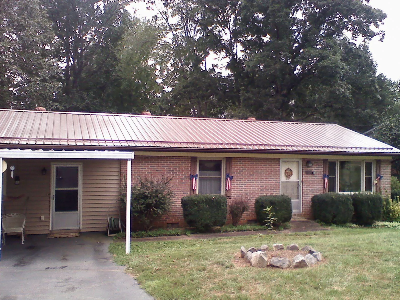 Bronze metal roof and carport on a brick ranch home — Roof Repair work by our crew in Comstock